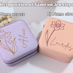 May include: Two square jewelry boxes, one lavender and one peach, with floral designs and personalized names. The lavender box has a lily of the valley design and the name "Alice". The peach box features a flower and the name "Lourdes". Text reads "Select position of Name on Jewelry Box".