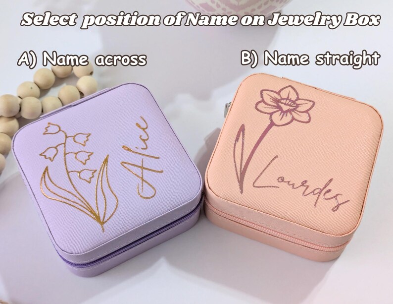 May include: Two square jewelry boxes, one lavender and one peach, with floral designs and personalized names. The lavender box has a lily of the valley design and the name "Alice". The peach box features a flower and the name "Lourdes". Text reads "Select position of Name on Jewelry Box".