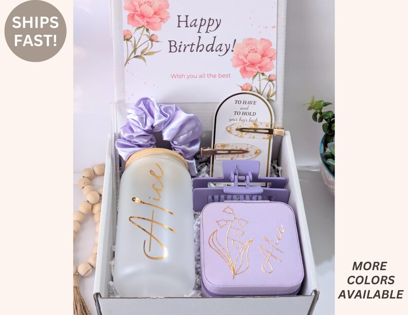 May include: A gift box with a birthday theme, containing a frosted glass with "Alice" in gold script, a lavender scrunchie, hair clips, and a lavender box with a floral design. The box includes a card that says "Happy Birthday!"