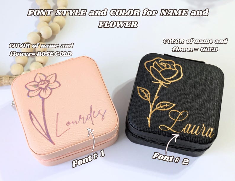 May include: Two square jewelry cases, one peach and one black. The peach case has a rose gold daffodil and the name "Lourdes" in a script font. The black case features a gold rose and the name "Laura".