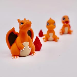 May include: Three orange and brown cartoon dragon figurines. The dragon in the foreground has a larger body and wings. The other two dragons are smaller and have no wings.