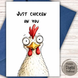 May include: A white greeting card featuring a cartoon chicken with wide, surprised eyes, a yellow beak, and a red comb and wattle. The text "JUST CHICKEN ON YOU" is printed in black above the chicken illustration on a plain white background.
