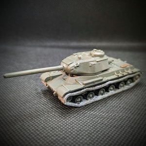 May include: A green toy tank with a detailed turret and tracks. The tank has a long barrel and is made of plastic.