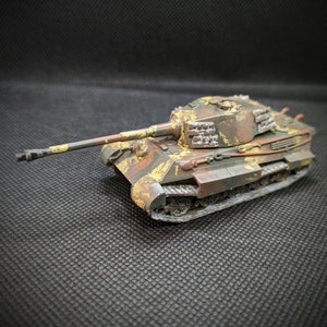 Puede incluir: Un modelo detallado de un tanque alemán King Tiger, pintado con un patrón de camuflaje verde, marrón y amarillo. El tanque tiene un cañón largo y orugas.