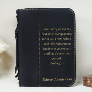 May include: Black leather Bible cover with a gold inscription that reads "Have mercy on me, my God, have mercy on me, for in you I take refuge. I will take refuge in the shadow of your wings until the disaster has passed. Psalm 57:1" and the name "Edward Anderson".