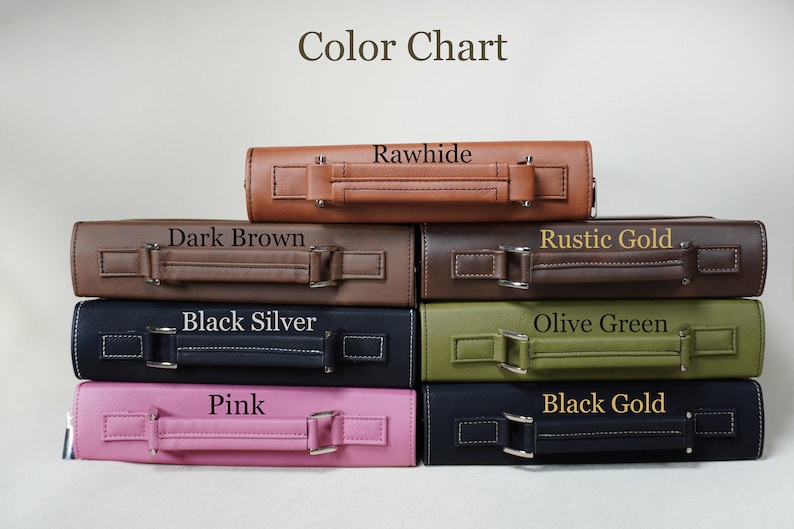 May include: A stack of six leather-bound books with different colored covers. The colors are rawhide, dark brown, black silver, olive green, pink, and black gold. The books have a handle on the top and are stacked on a white surface.