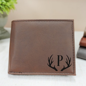 May include: A brown leather wallet with a monogrammed initial "P" surrounded by antlers.