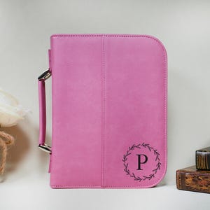 May include: A pink faux leather bible cover with a silver handle and a monogrammed initial "P" in a wreath design.