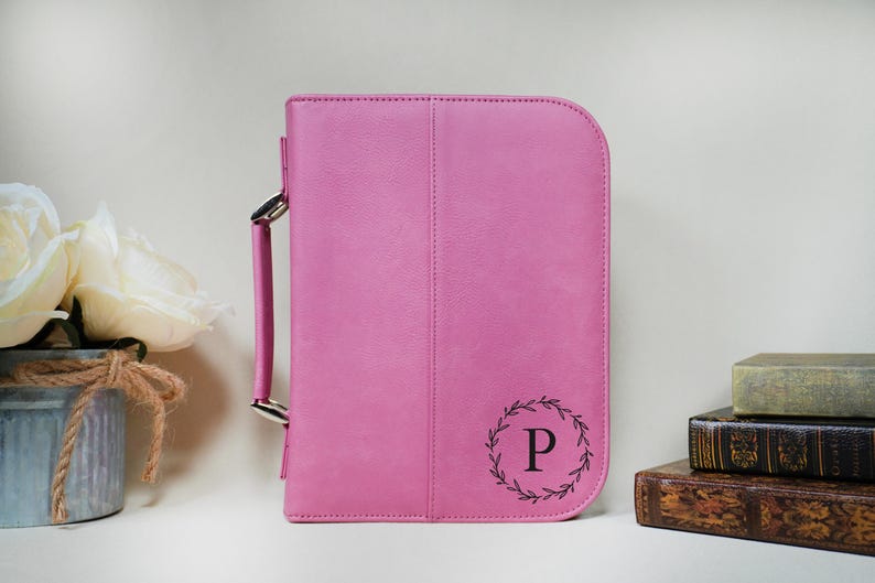 May include: A pink faux leather bible cover with a silver handle and a monogrammed initial "P" in a wreath design.