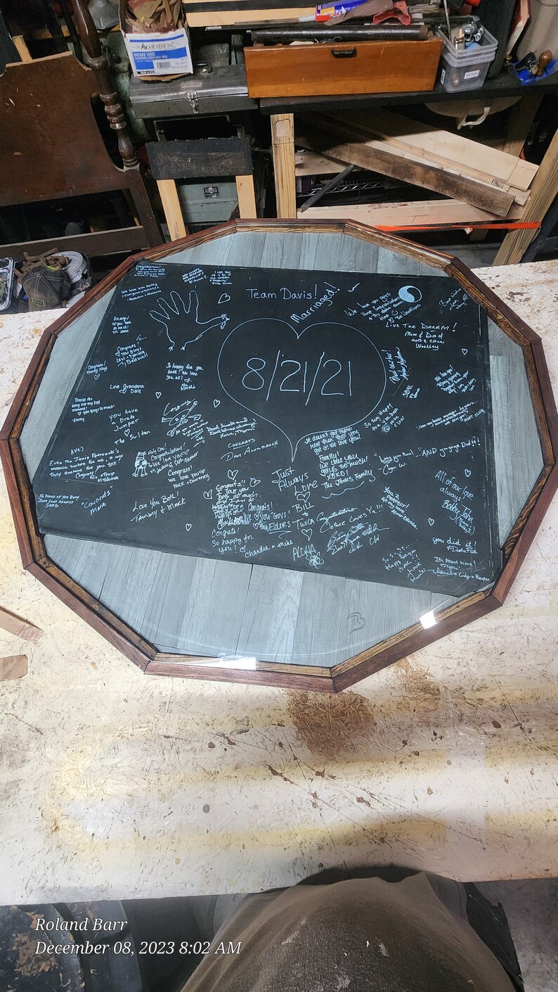 May include: A black octagonal tabletop with a glass top, covered in handwritten messages and drawings, including a heart with the date "8/21/21" and the words "Team Davis! Married!"