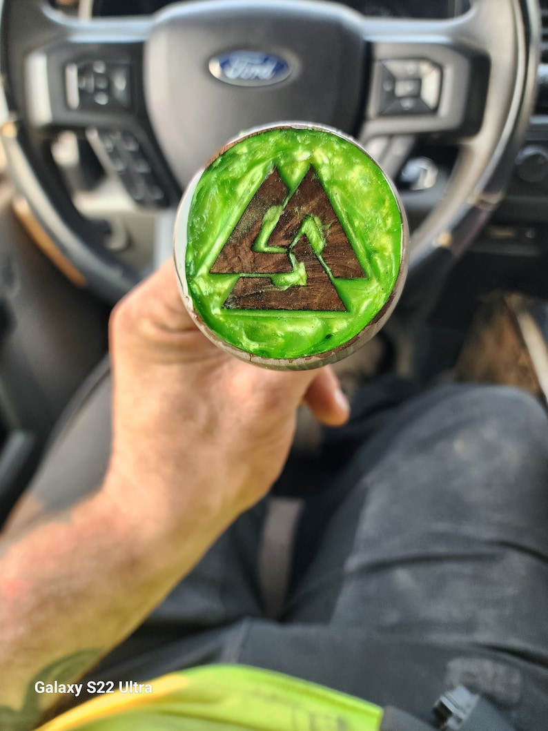 May include: A green and brown wooden knob with a triangular design. The knob is made of wood and has a green epoxy finish.