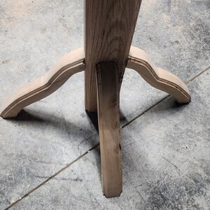 May include: A wooden table leg with a three-pronged base. The base is made of three pieces of wood that are joined together at the top. The wood is a light brown colour and has a natural finish.