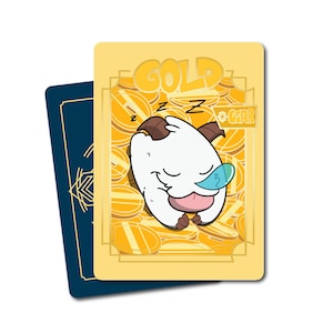 May include: A rectangular playing card with a yellow background featuring a white creature with horns sleeping on a pile of gold coins. The word GOLD is printed at the top, and the word GEAR is inside a small box on the right. A dark blue card is behind it.