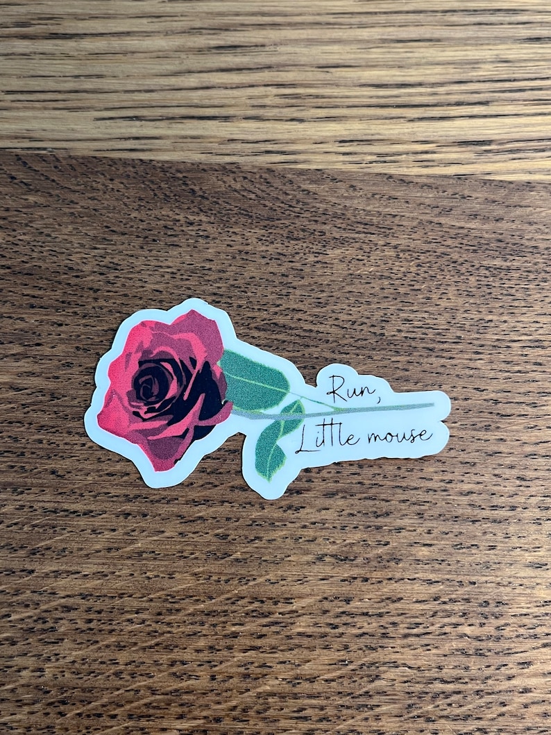 May include: A sticker with a red rose and the text "Run, little mouse" in black cursive.