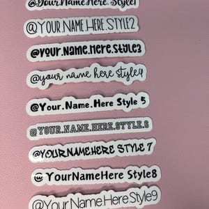 Peut inclure: Neuf autocollants blancs avec du texte noir montrant différents styles du texte "@Your Name Here" pour les noms d'utilisateur des médias sociaux.