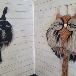 May include: Two owl wall hangings, one black and white and one brown and white, with a wooden branch and a heart-shaped detail on each owl's chest.