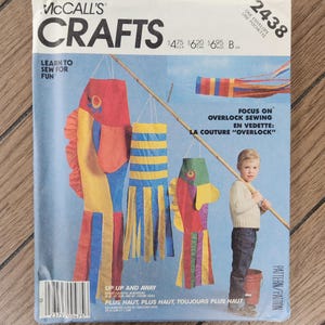 May include: A McCall's Crafts sewing pattern envelope 2438 featuring illustrations of three colorful fish-shaped windsocks and a striped windsock. The text includes Learn to Sew for Fun, Focus on Overlock Sewing, and Up Up and Away.