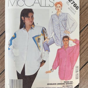 Può includere: Una busta per cartamodello McCall's 2766 per una camicia abbottonata in taglia media. La copertina presenta illustrazioni di tre varianti di camicia: una bianca con accenti geometrici blu e gialli, una con un davanti blu a motivi e una rosa a tinta unita.