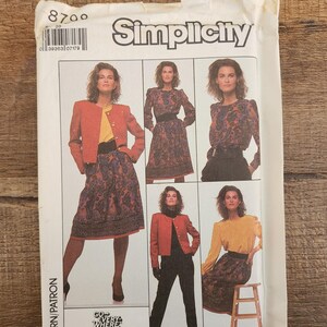 以下が含まれることがあります： Simplicityの型紙封筒、番号8700。赤いジャケット、黄色いトップス、ペイズリー柄のスカート、黒いズボンなど、様々な服装のイラストが描かれています。テキストにはSimplicity、8700、Go Every Whereと記載されています。