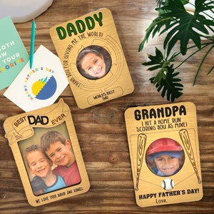 May include: Three wooden Father's Day cards with photo frames and personalized messages. The first card says "Daddy, Thank you for giving me the world!" The second card says "Best Dad Ever" and the third card says "Grandpa, I hit a home run scoring you as mine! Happy Father's Day! Love."