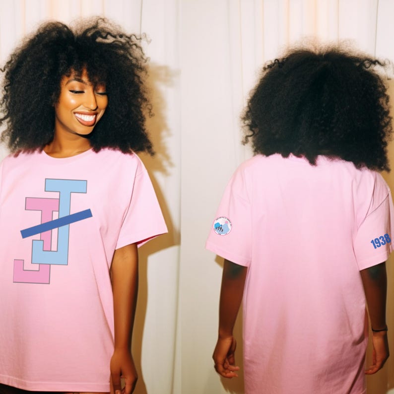 Peut inclure: T-shirt rose clair avec un motif g&eacute;om&eacute;trique bleu clair et rose. Le t-shirt a des manches courtes et un col rond. Le dos du t-shirt porte un petit &eacute;cusson et le chiffre "1938" imprim&eacute; en bleu.