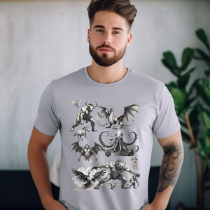 Male model with tattoo in one arm wearing Silver colored short sleeve shirt standing in a room with a plant on base behind him