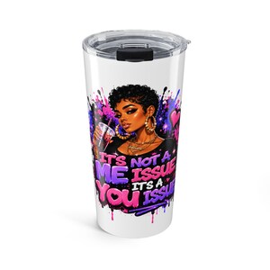 May include: A white stainless steel tumbler with a clear plastic lid featuring a graphic of a person with short dark hair, gold hoop earrings, and a necklace. The text reads, "IT'S NOT A ME ISSUE IT'S A YOU ISSUE" in purple and pink paint-drip style.