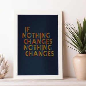 May include: A framed print with the text "IF NOTHING CHANGES NOTHING CHANGES" in colourful retro lettering. The artwork is displayed on a white wall, next to a decorative plant in a beige vase and a white decorative object.