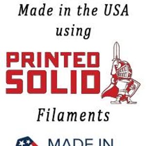 K&ouml;nnte beinhalten: Ein rot-wei&szlig;es Logo mit dem Text "PRINTED SOLID" und den Worten "Proudly Made in the USA using Filaments MADE IN AMERICA" darunter.