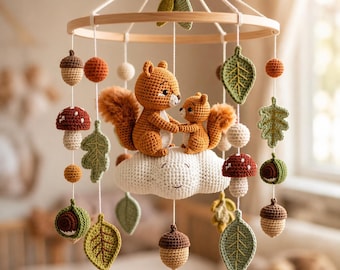 May include: A crochet nursery mobile featuring a large and small squirrel sitting on a white cloud. The mobile includes hanging elements such as green leaves, brown acorns, and red-and-white spotted mushrooms suspended from a circular wooden frame.