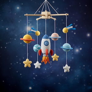 Op de afbeelding: Handgemaakte baby mobile met een ruimtethema, inclusief een raket, planeten, sterren en kometen. De raket is wit met blauwe en rode accenten. Planeten zijn geel, blauw en gestreept. Sterren zijn geel en wit. De mobile hangt aan een houten frame tegen een sterrenachtergrond.