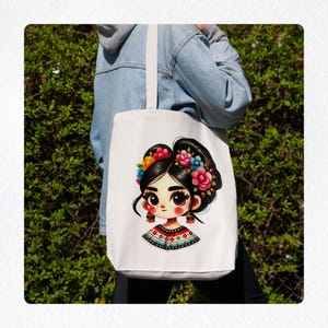 Puede incluir: Una bolsa de tela blanca con una ilustraci&oacute;n colorida de una ni&ntilde;a con flores en el pelo. La ni&ntilde;a lleva una camisa con estampado colorido y pendientes.