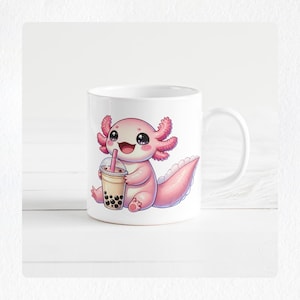 May include: White ceramic mug featuring a cartoon axolotl holding a boba tea. The axolotl is pink with large eyes and a smiling expression. The boba tea is in a clear cup with a pink straw. The mug has a white handle.