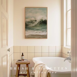 K&ouml;nnte beinhalten: Eine wei&szlig;e Badewanne mit einem wei&szlig;en Handtuch &uuml;ber dem Rand, die in einem Badezimmer mit cremefarbenen Fliesenw&auml;nden steht. &Uuml;ber der Wanne h&auml;ngt ein gerahmtes Bild von einem st&uuml;rmischen Meer. Der Text "BRUSH & PALETTES art collective" ist in der rechten unteren Ecke des Bildes zu sehen.