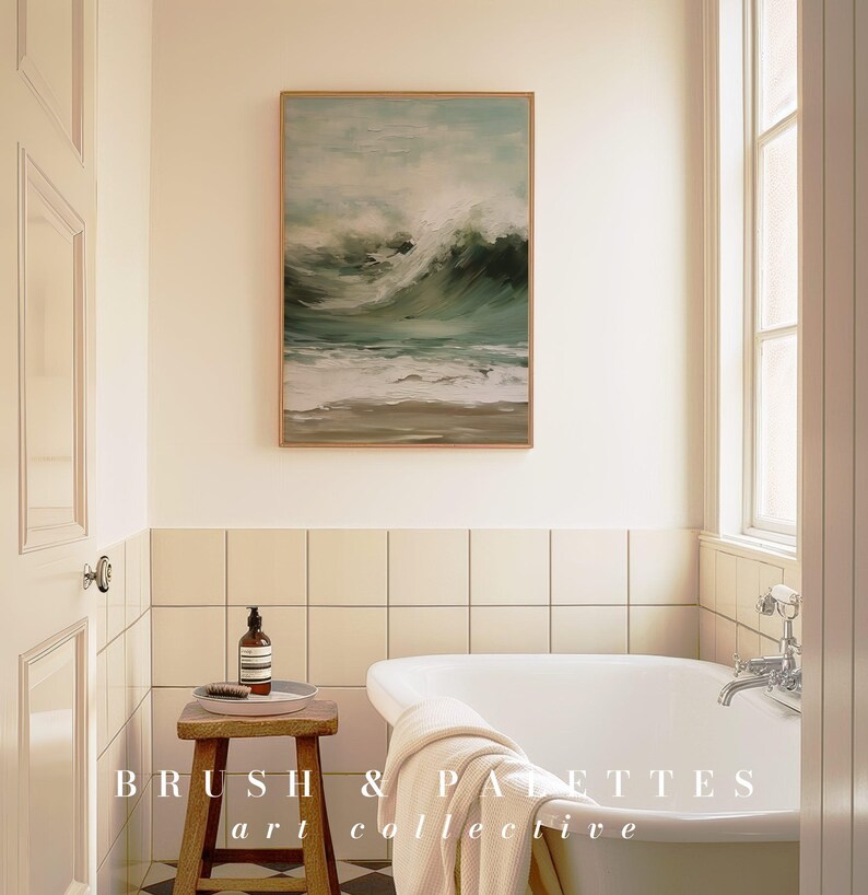 K&ouml;nnte beinhalten: Eine wei&szlig;e Badewanne mit einem wei&szlig;en Handtuch &uuml;ber dem Rand, die in einem Badezimmer mit cremefarbenen Fliesenw&auml;nden steht. &Uuml;ber der Wanne h&auml;ngt ein gerahmtes Bild von einem st&uuml;rmischen Meer. Der Text "BRUSH & PALETTES art collective" ist in der rechten unteren Ecke des Bildes zu sehen.
