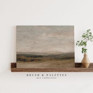 May include: A landscape painting with a muted color palette of beige, brown, and gray tones. The artwork depicts rolling hills under a cloudy sky. The painting is displayed on a wooden shelf with a small vase of greenery.