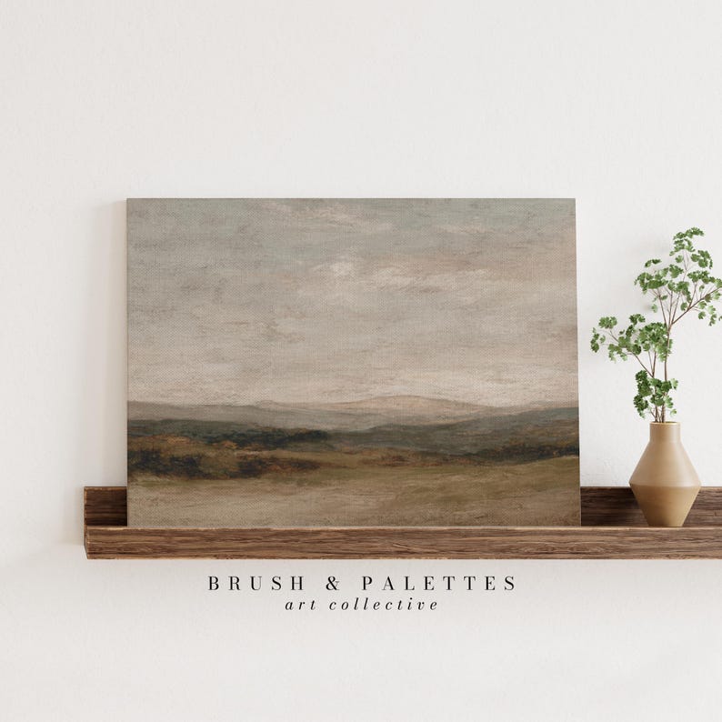 May include: A landscape painting with a muted color palette of beige, brown, and gray tones. The artwork depicts rolling hills under a cloudy sky. The painting is displayed on a wooden shelf with a small vase of greenery.