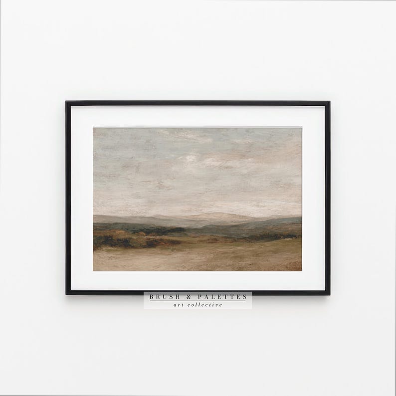 May include: Framed landscape art print featuring a muted color palette of beige, green, and gray. The artwork depicts a serene countryside scene with rolling hills and a cloudy sky. The text "BRUSH & PALETTES art collective" is at the bottom.
