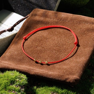 Immerse yourself in the essence of minimalist beauty and spiritual safeguarding with our Triple Gold Bead Fine Red Protection Cord Bracelet. Perfectly blending subtle elegance with meaningful protection