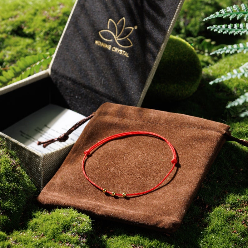 Immerse yourself in the essence of minimalist beauty and spiritual safeguarding with our Triple Gold Bead Fine Red Protection Cord Bracelet. Perfectly blending subtle elegance with meaningful protection