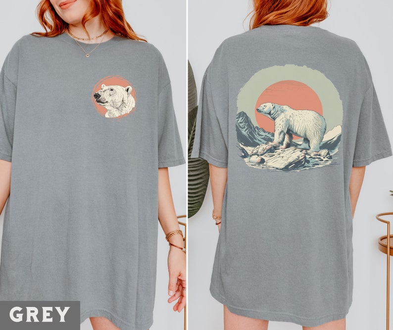 May include: A grey t-shirt with a graphic of a polar bear standing on a rock in front of a sunset. The graphic is on the back of the shirt.