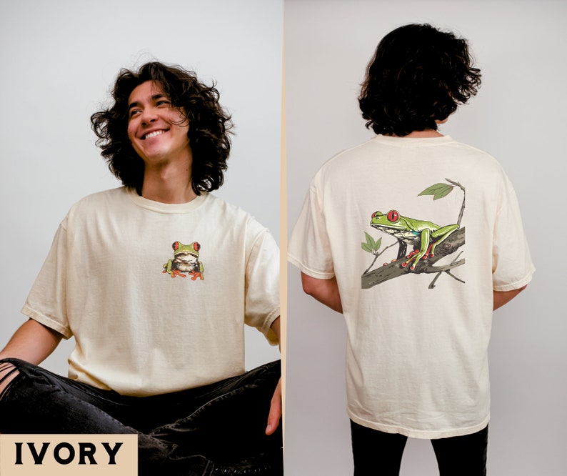 May include: A cream colored t-shirt with a green tree frog on the front and a larger green tree frog on the back. The text "IVORY" is at the bottom of the image.