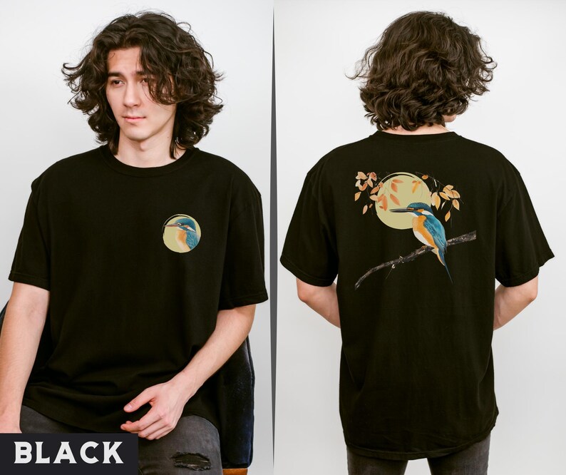 Puede incluir: Camiseta negra con un gr&aacute;fico de un p&aacute;jaro azul y verde en una rama con una luna amarilla en el fondo. El p&aacute;jaro est&aacute; posado en una rama con hojas. La camiseta tiene cuello redondo y mangas cortas.