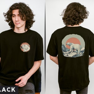 May include: A black t-shirt with a graphic of a polar bear standing on a snowy mountain with a red sun in the background. The front of the shirt has a smaller graphic of a polar bear's head.