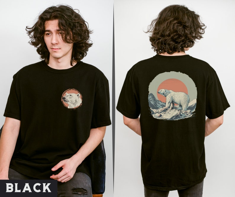 May include: A black t-shirt with a graphic of a polar bear standing on a snowy mountain with a red sun in the background. The front of the shirt has a smaller graphic of a polar bear's head.