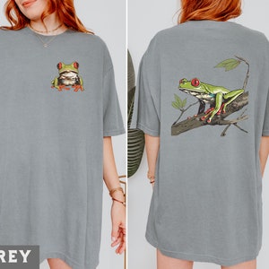 May include: Two gray t-shirts with a green tree frog graphic. One shirt has the frog on the front and the other has the frog on the back.