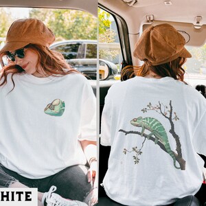 May include: White t-shirt with a chameleon graphic on the front and a chameleon on a branch graphic on the back.