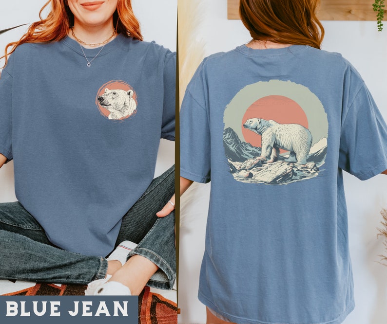 May include: A blue jean t-shirt with a polar bear graphic on the front and a polar bear graphic with a sunset in the background on the back. The shirt is made of a soft, comfortable material.
