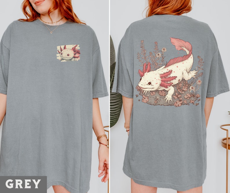 May include: A grey t-shirt with a pink and white axolotl illustration on the front. The axolotl is surrounded by pink flowers and leaves.