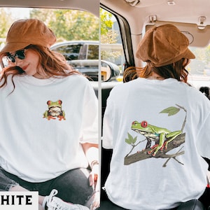 May include: White t-shirt with a green tree frog graphic on the front and a green tree frog on a branch graphic on the back.